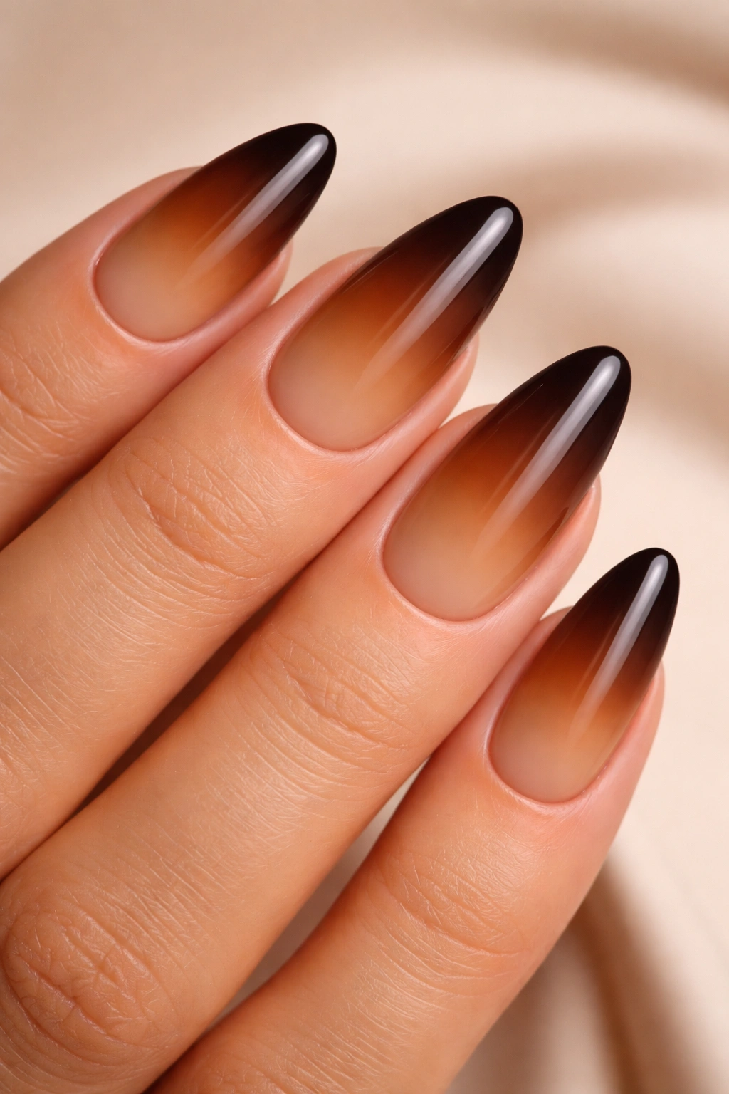 Close-up of almond nails with a caramel to espresso ombre gradient