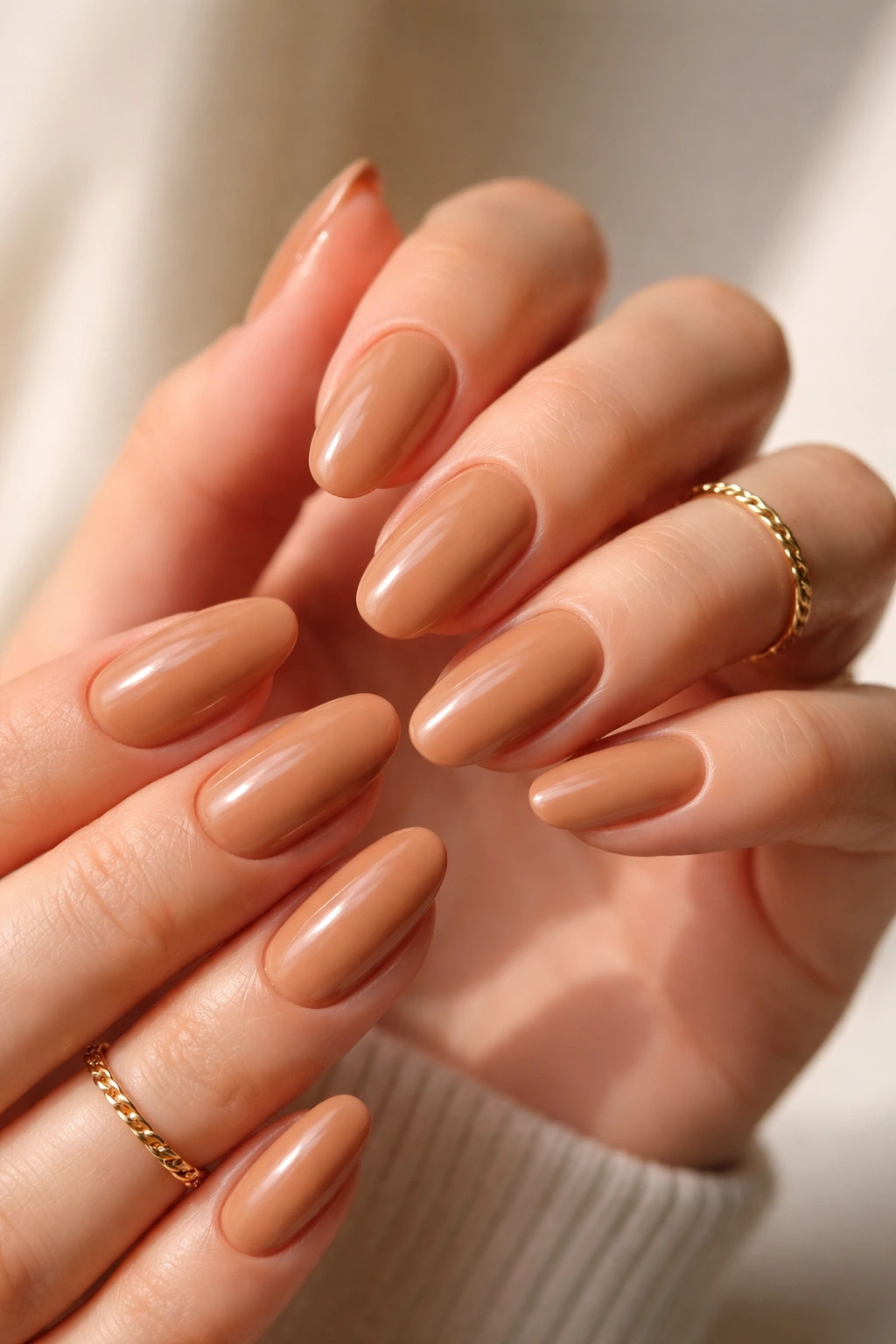 Close-up of hands with nails painted warm caramel latte shade, glossy tan manicure