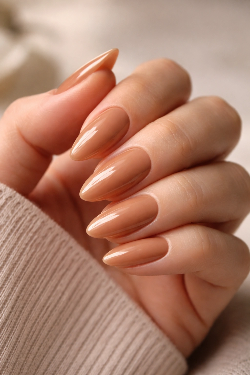 Close-up of caramel nude almond nails on a hand
