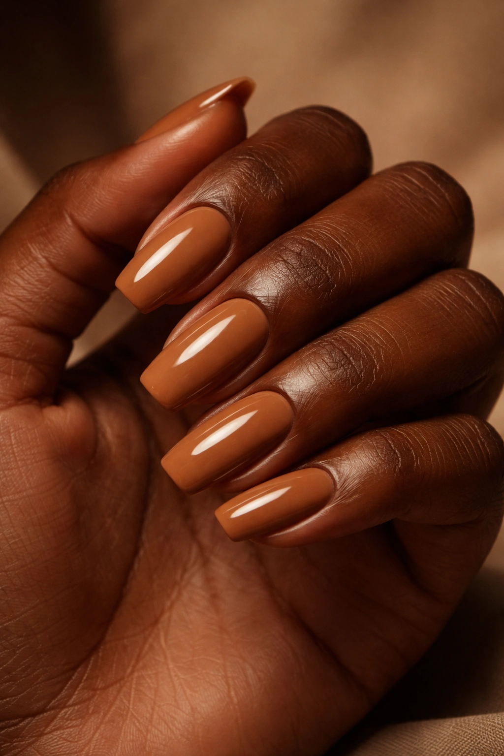 Close-up of dark-skinned hand with rich caramel nude nails