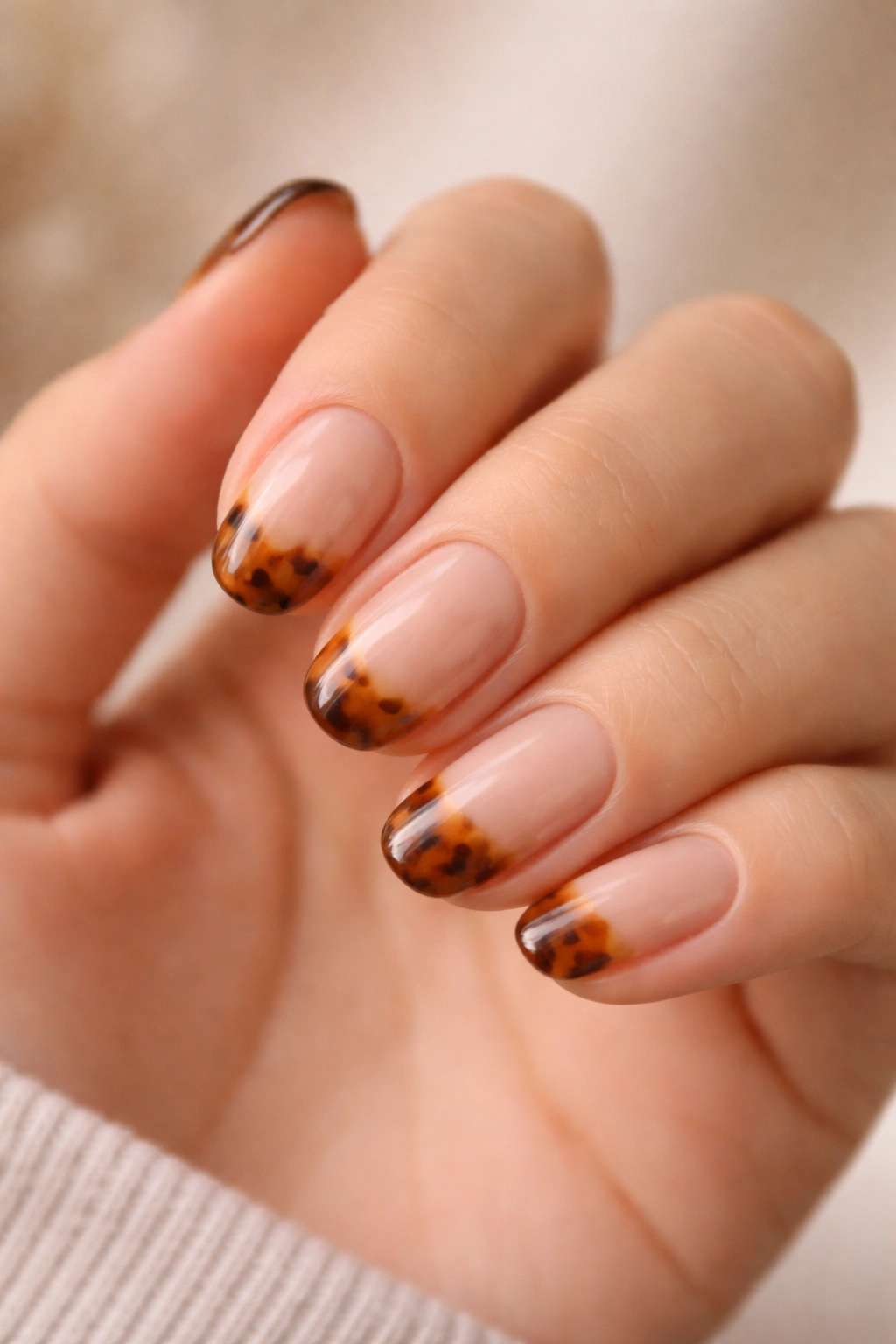 Close-up of caramel tortoiseshell tip nails on short oval nails