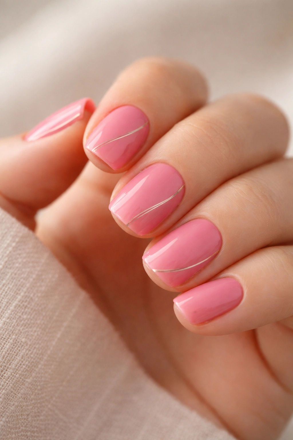 Close-up of carnation pink nails with delicate fine white or gold lines.