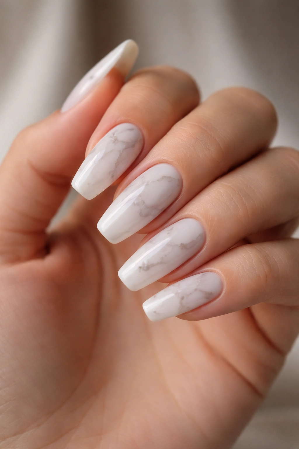 Milky white Carrara marble nails on a medium-length ballerina shape hand