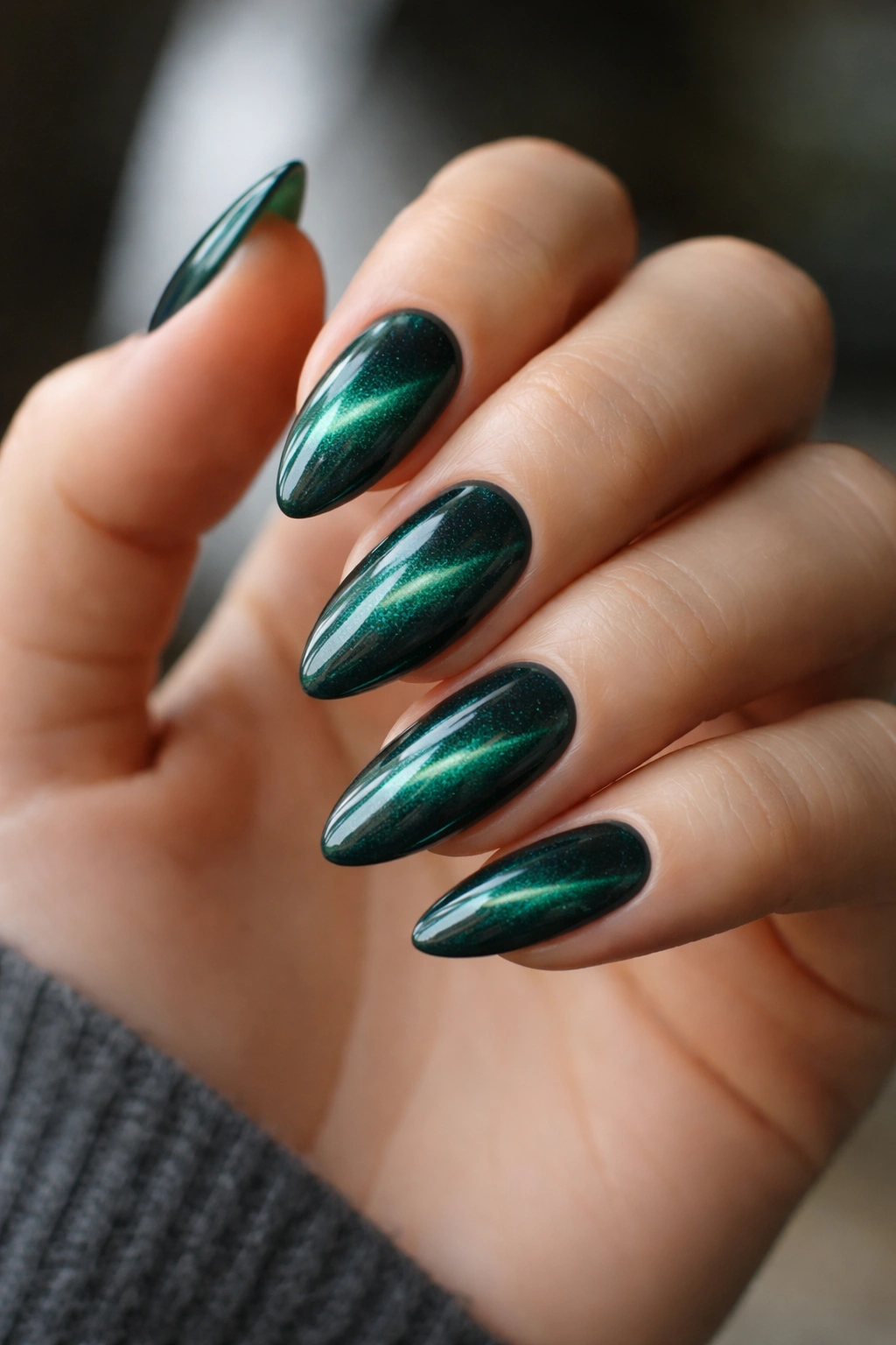 Close-up of emerald velvet cat-eye almond nails on a hand