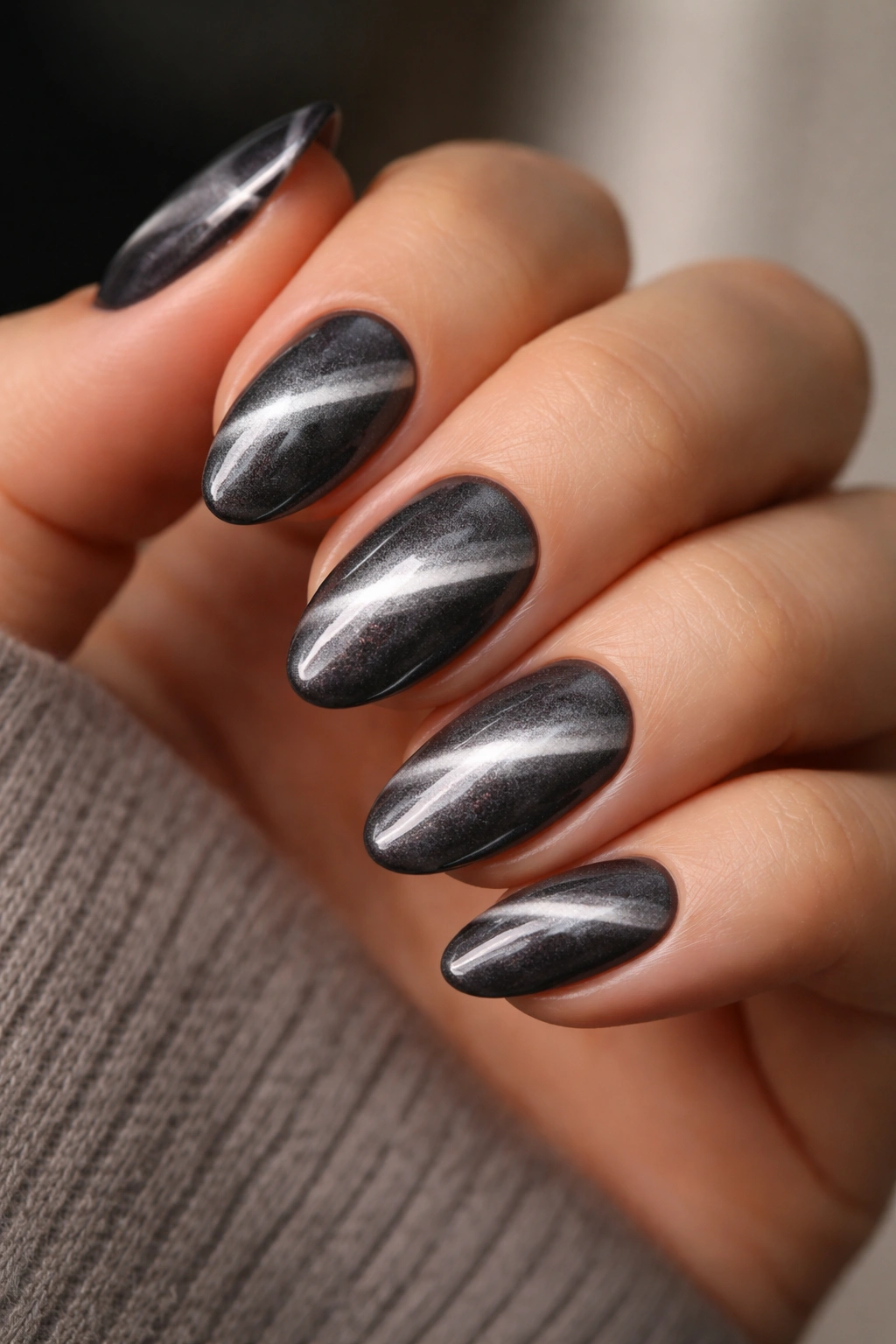 Close-up of silver cat-eye almond nails on a hand
