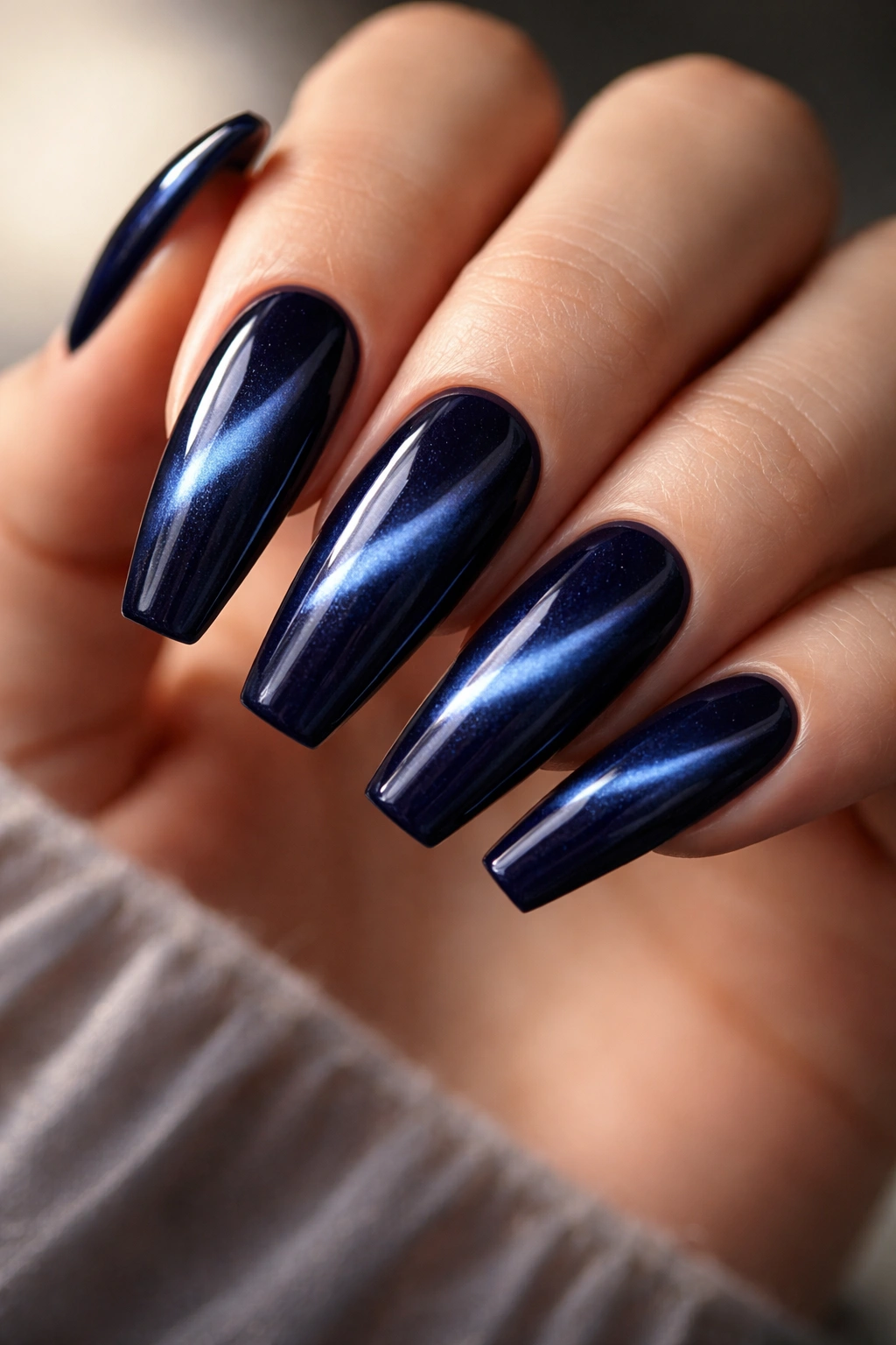 Close-up of dark blue cat-eye nails showing a shifting light band