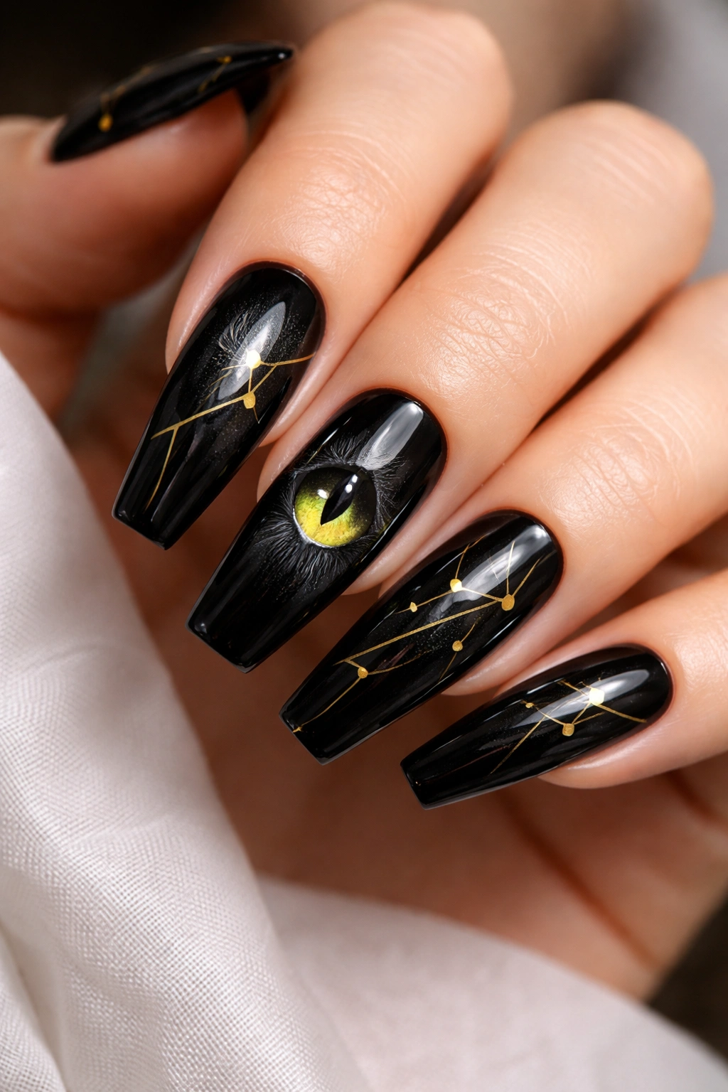 Close-up of coffin nails showing a black cat eye on one nail and gold geometric accents on the others
