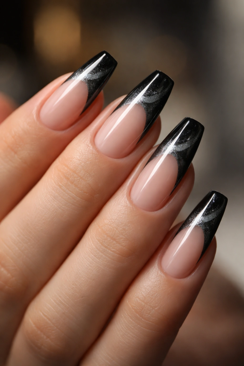 Nude-based nails with black cat-eye tips showing shifting sheen