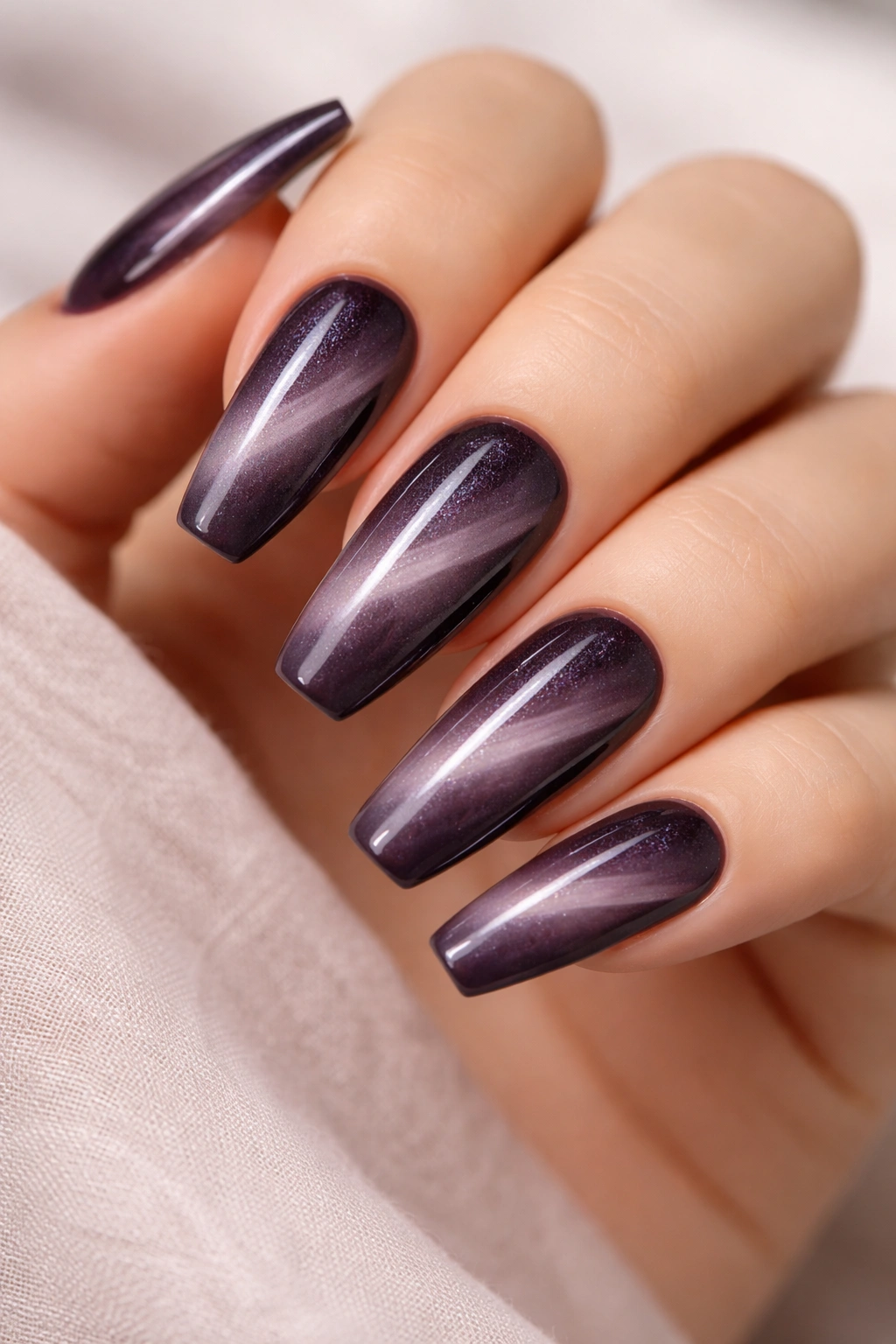 Smoky plum cat eye fade nails with a diagonal beam on a neutral background