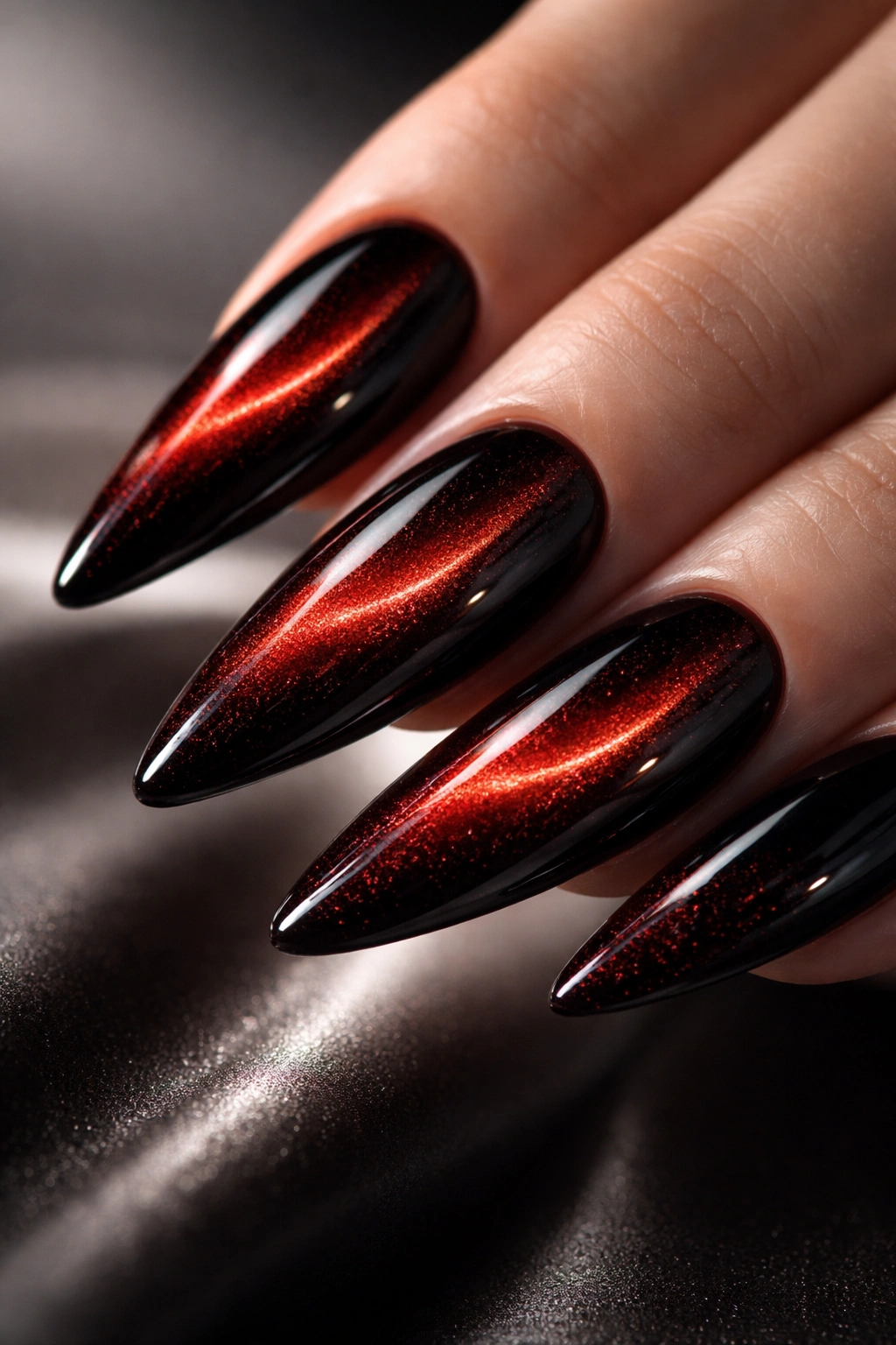 Close-up of nails with deep red cat-eye shimmer and black accents