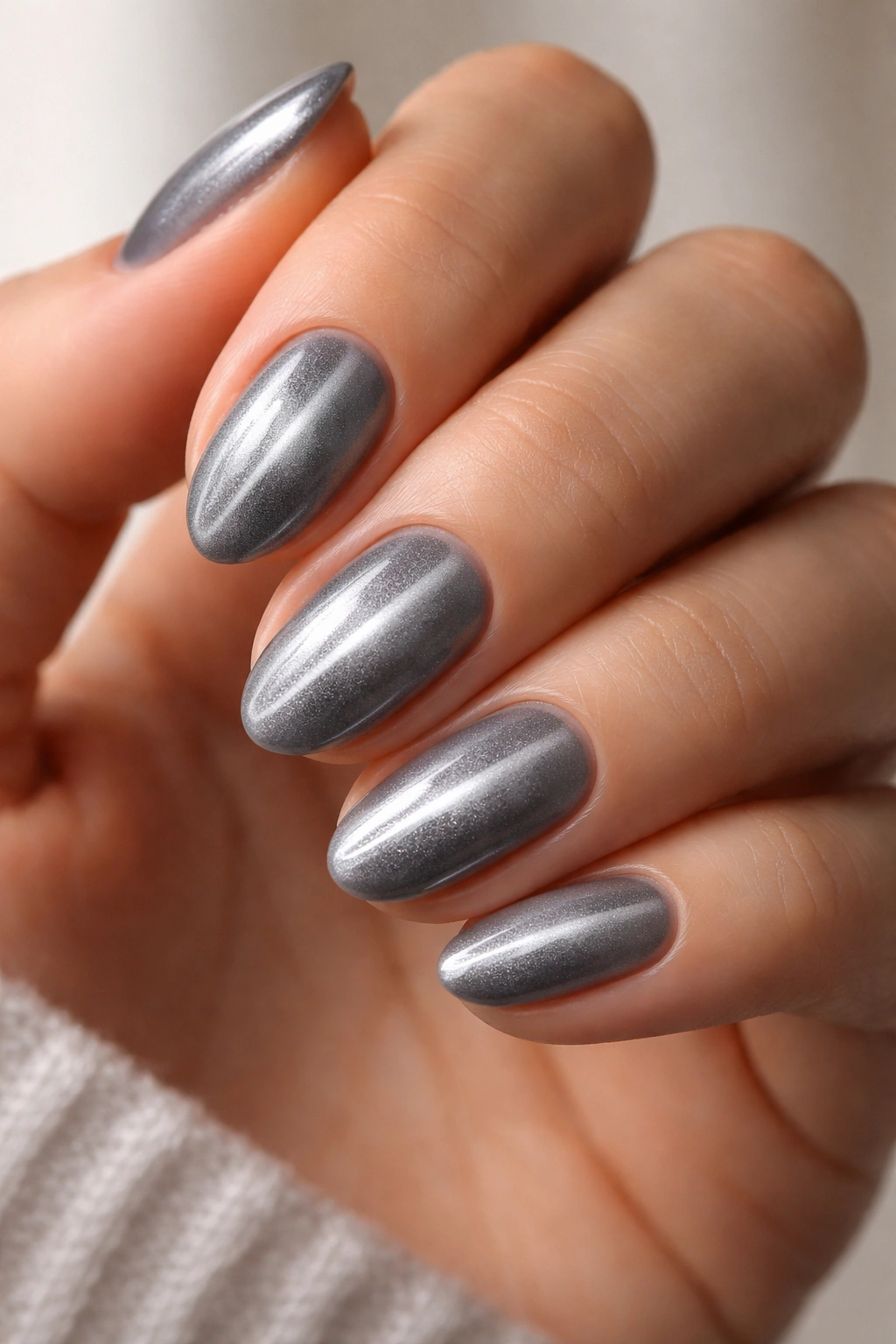 Close-up of soft silver cat-eye nails on short almond nails with centered magnetic stripe
