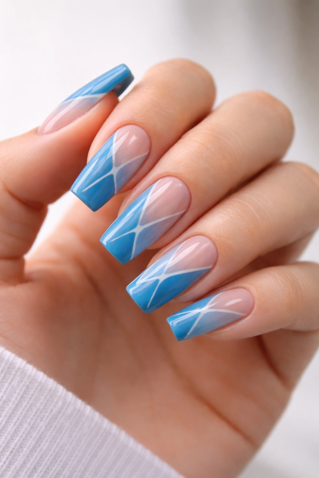 Close-up of medium coffin nails in cerulean blue with negative space geometric patterns