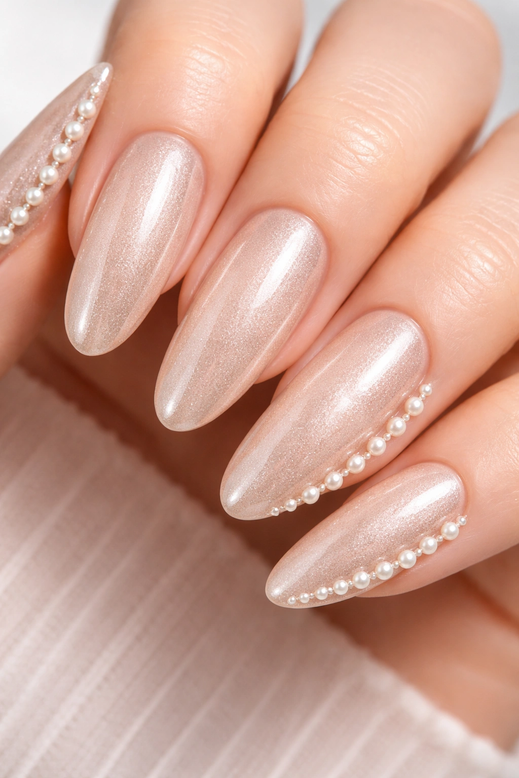 Nail with champagne shimmer and pearl embellishment along outer edge