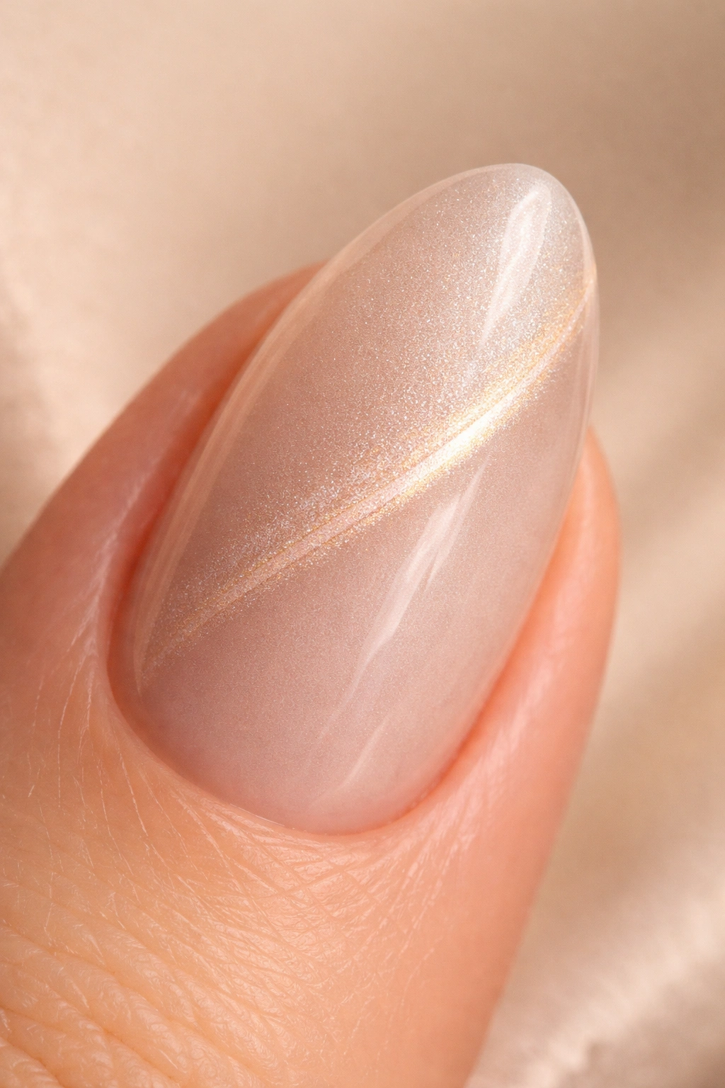 Close-up of a short almond nail with champagne pearl cat-eye shimmer