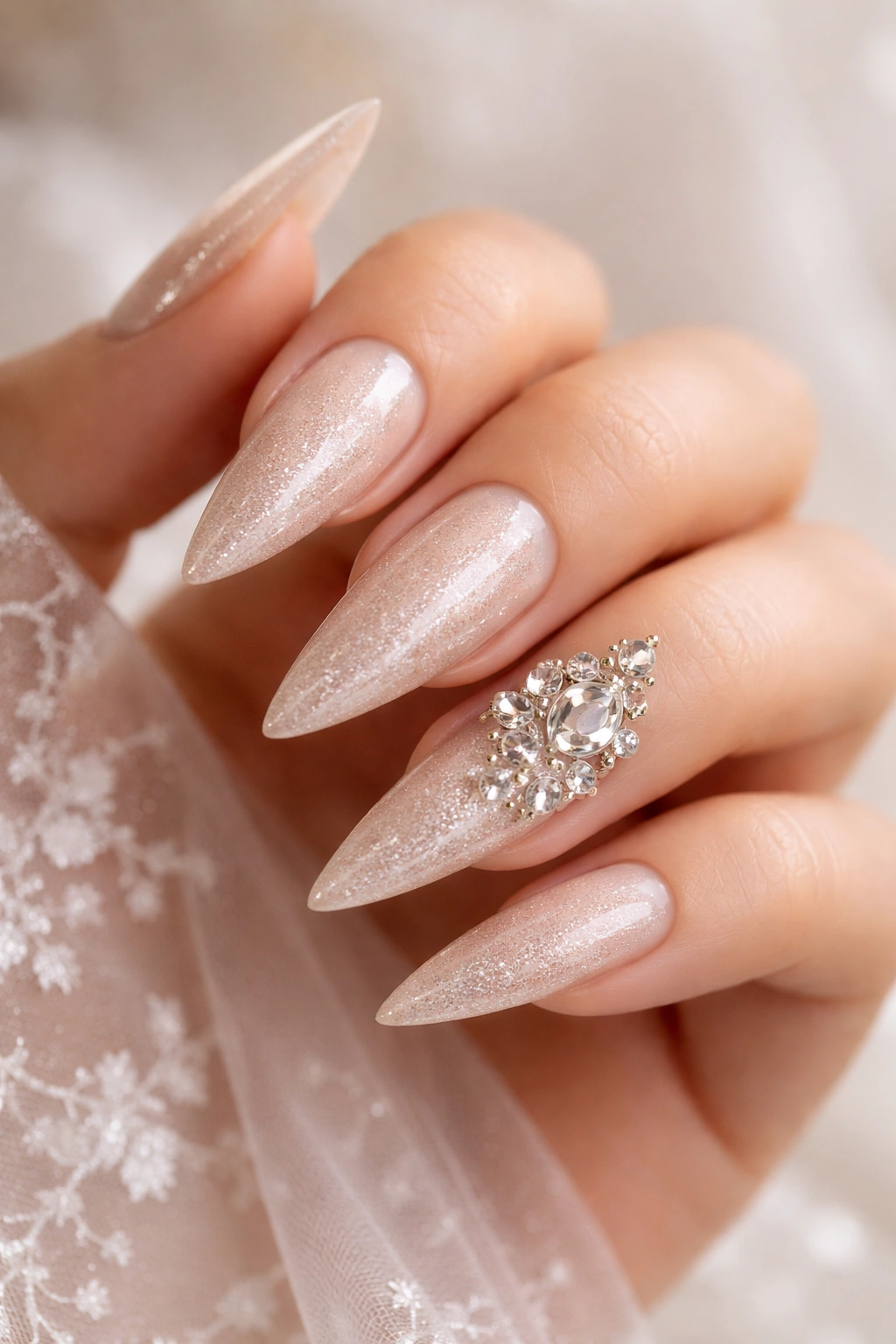 Close-up of stiletto nails with champagne shimmer and crystal clusters on ring finger