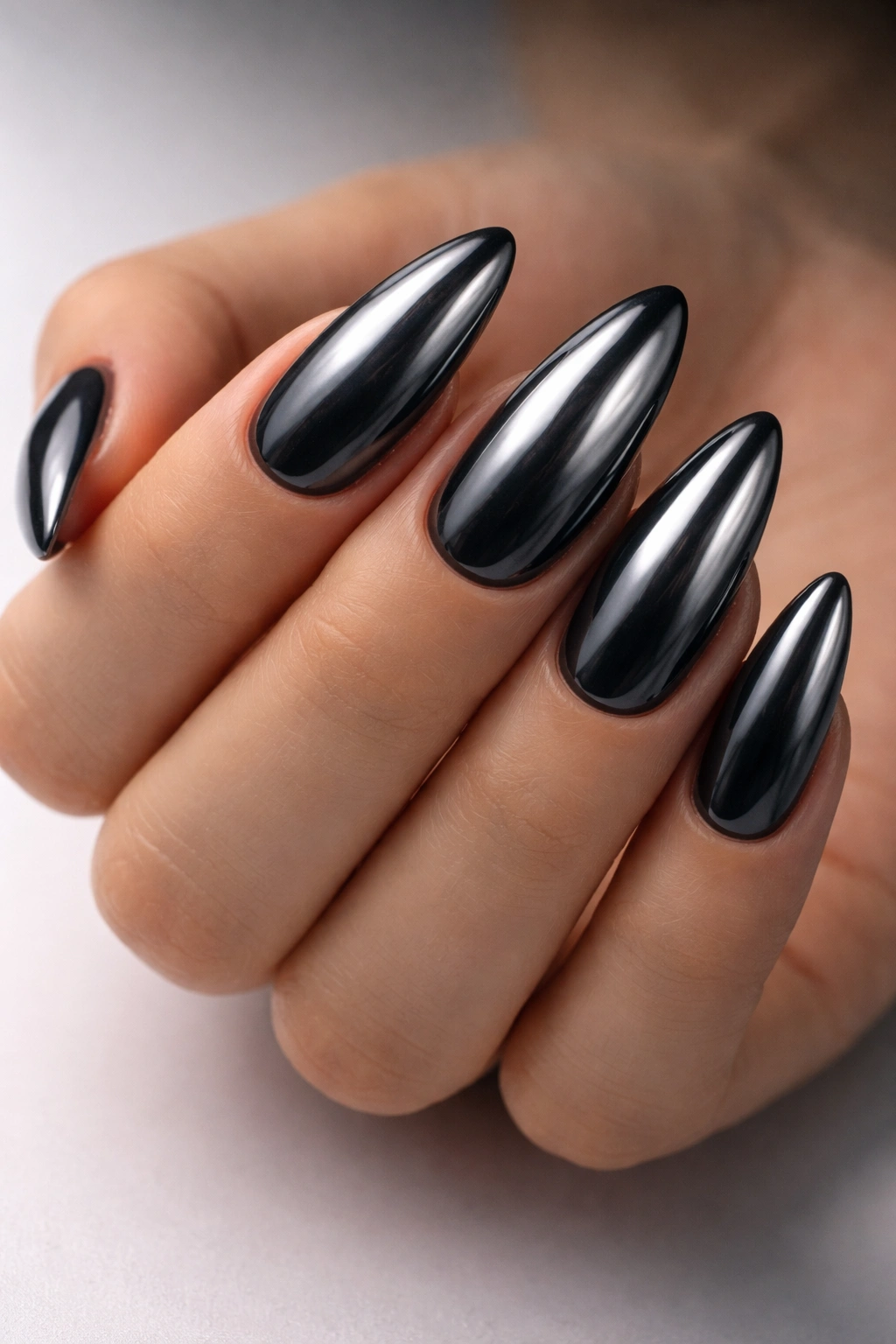 Close-up of charcoal chrome almond nails with reflective metallic finish