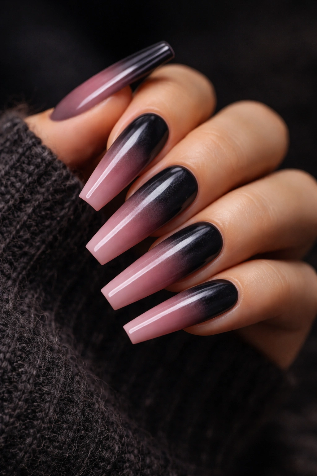 Close-up of long coffin nails in charcoal to dusty rose ombre on a dark background