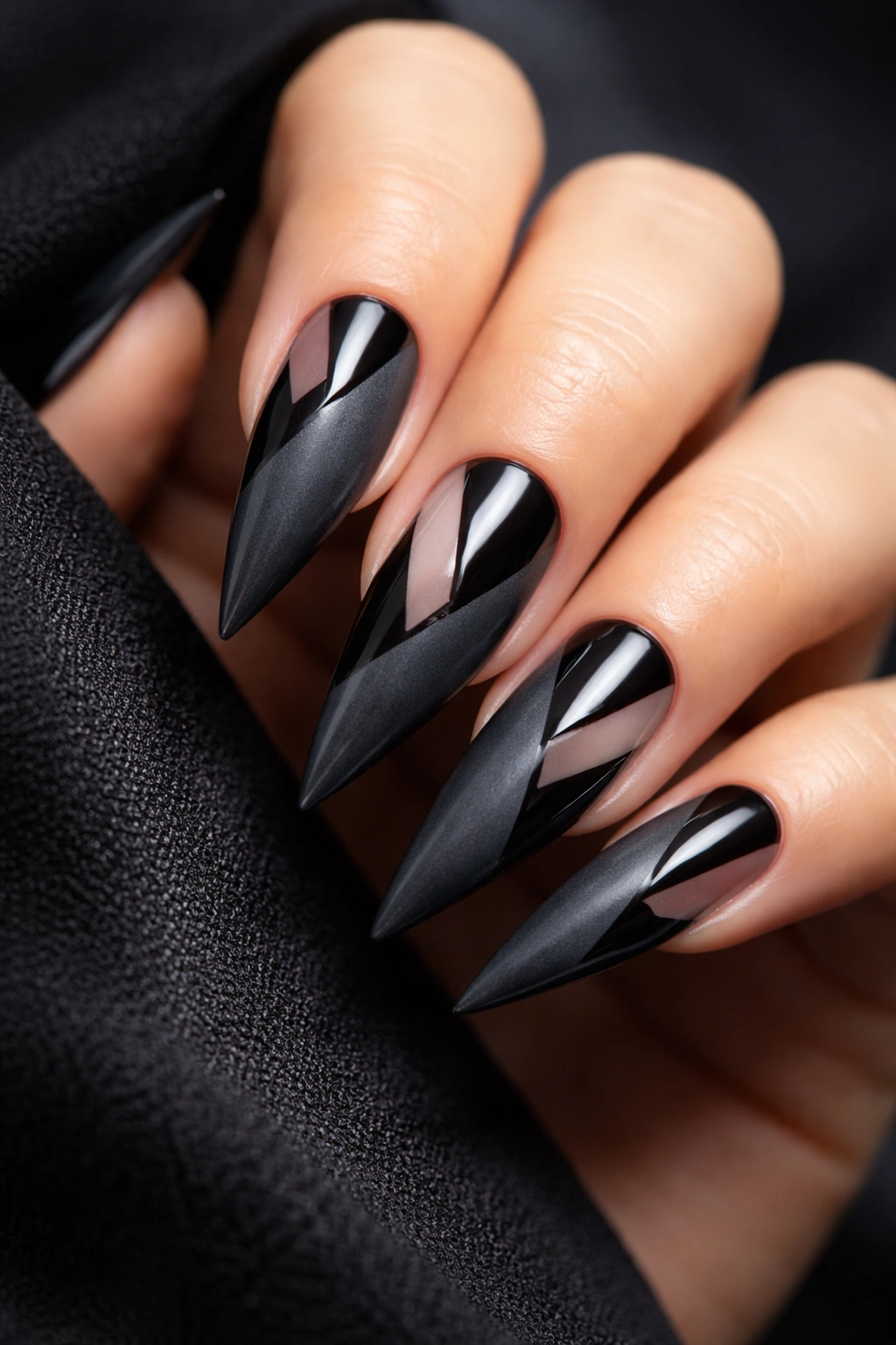 Close-up of charcoal gray stiletto nails with black geometric shapes and negative space