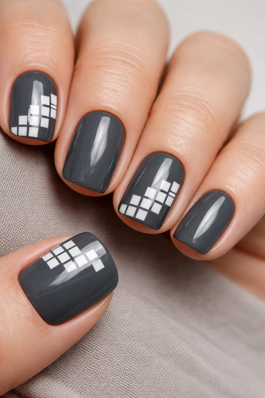 Close-up of charcoal gray nails with a small white tile geometry on short squoval nails.