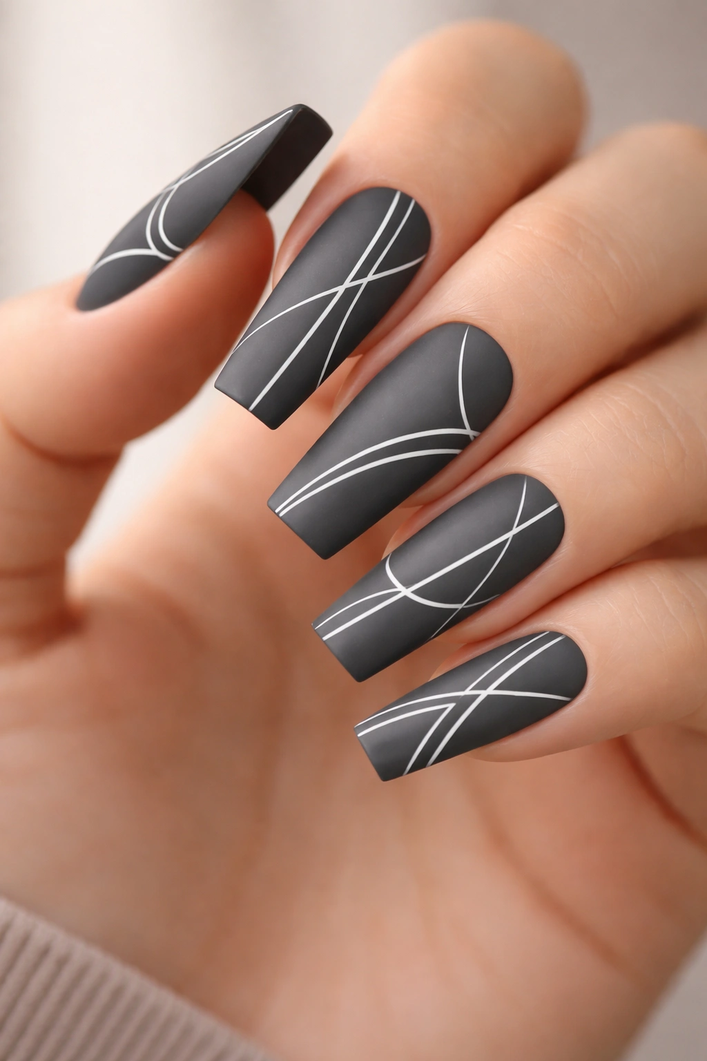 Close-up of charcoal gray coffin nails featuring minimalist white line art