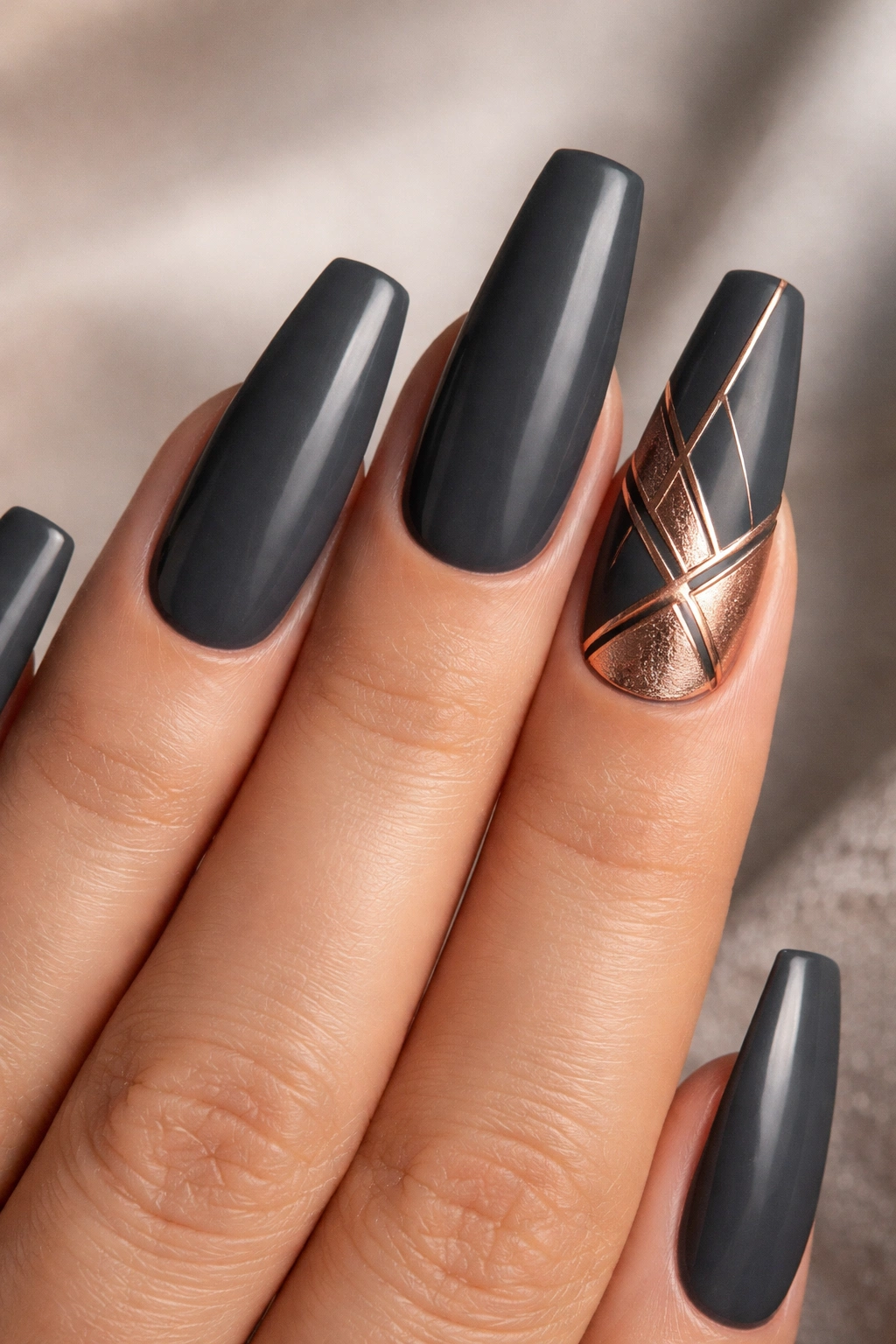 Charcoal gray coffin nails with rose gold geometric inlay on an accent nail
