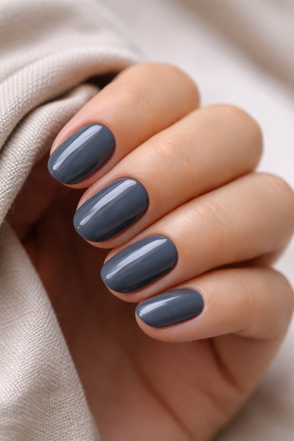 Close-up of charcoal gray short oval nails with blue undertone creme
