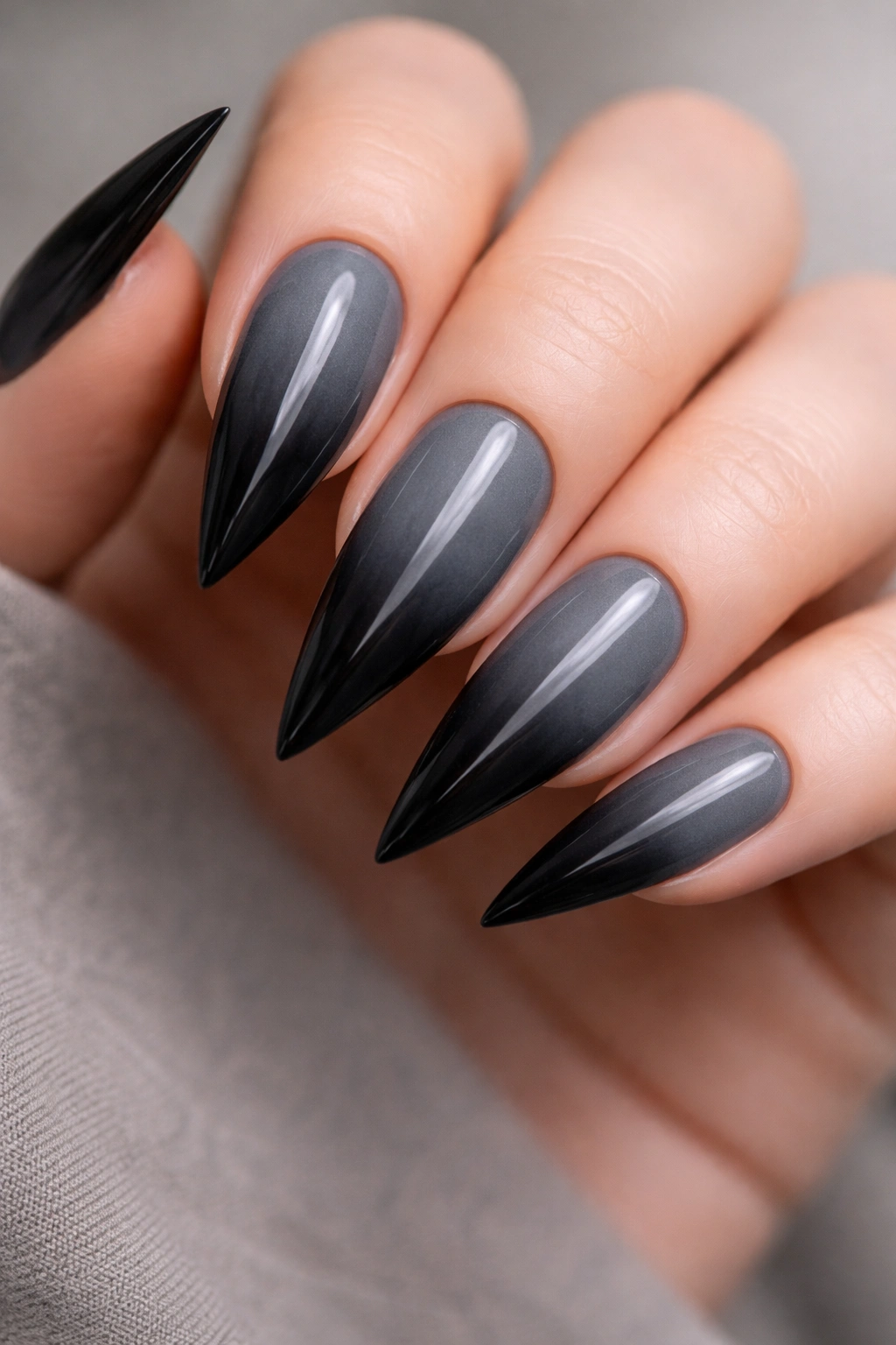 Charcoal gray stiletto nails fading to black toward the tips with a smoky ombre