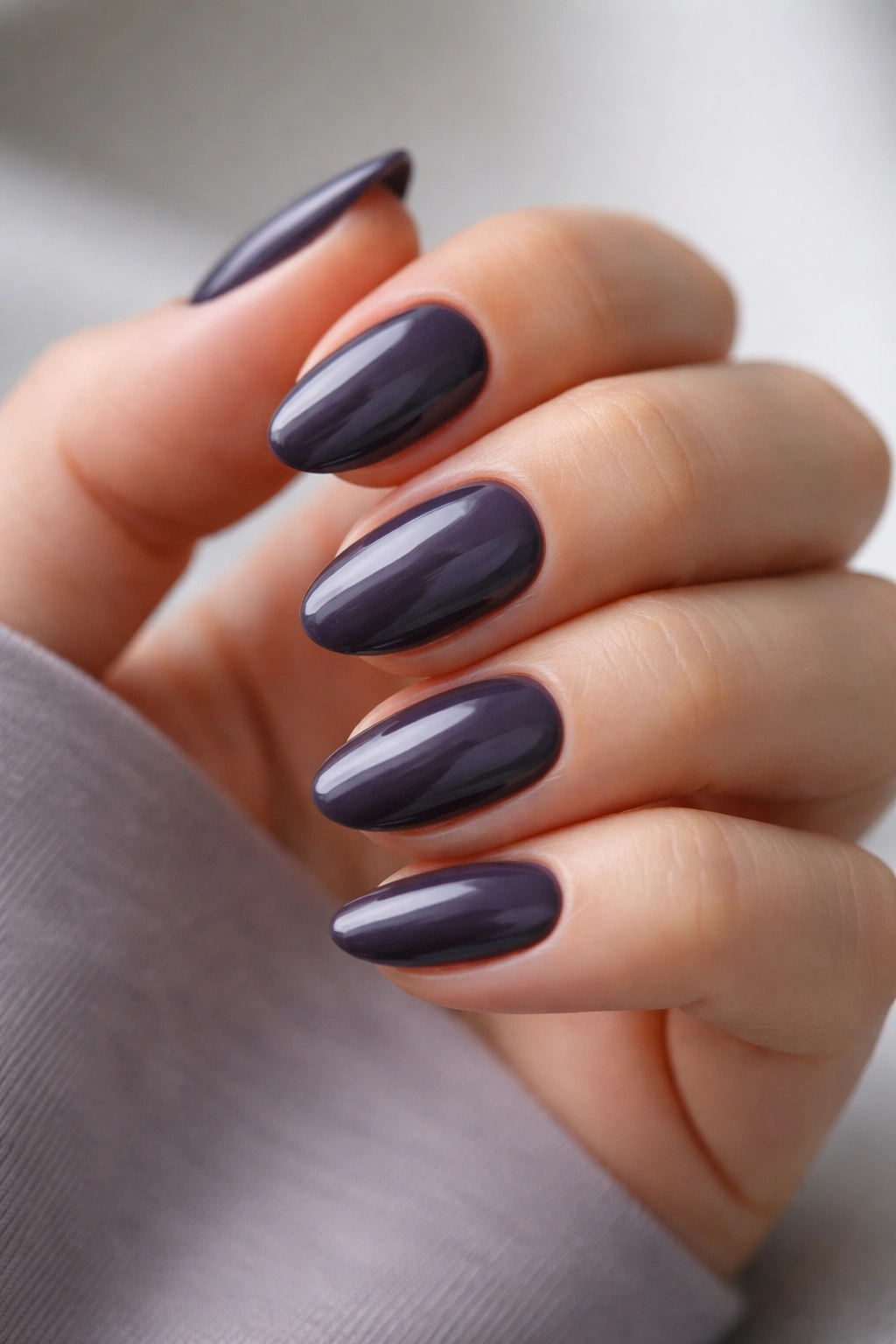 Close-up of short almond nails in charcoal plum shade with gray undertone