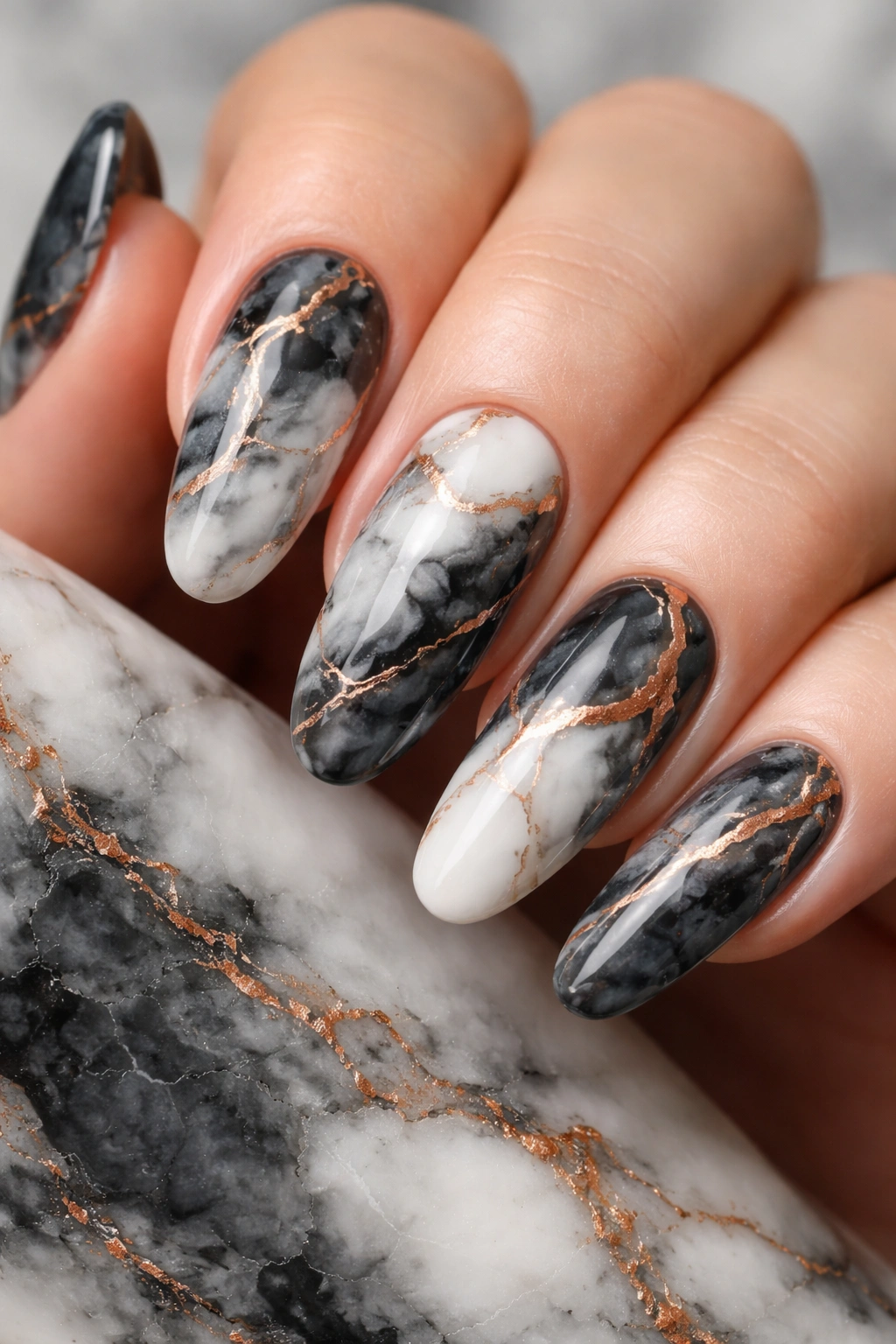 Close-up of long round nails with charcoal and white marble and copper accents.