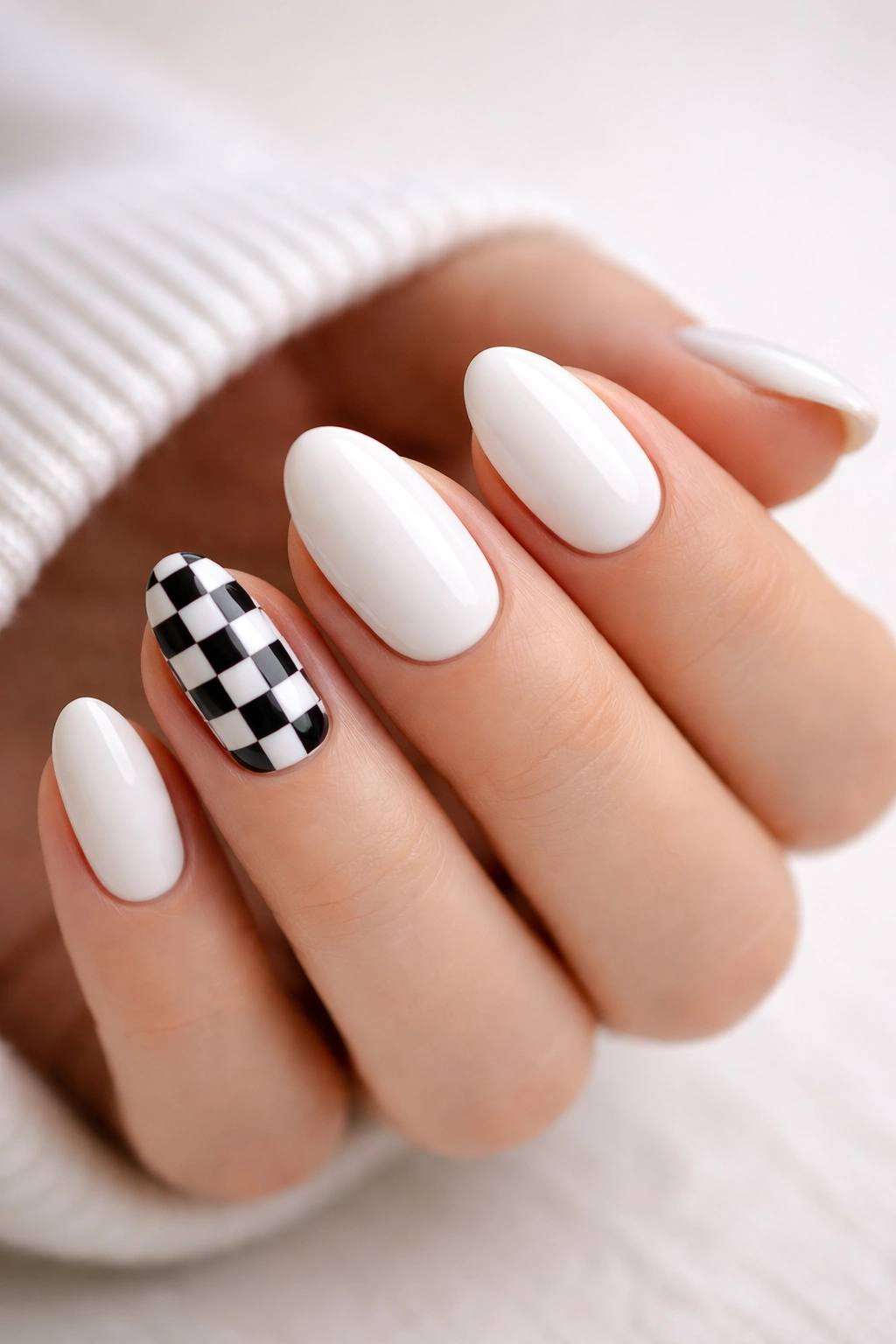 Close-up of white almond nails with a black-and-white checker accent