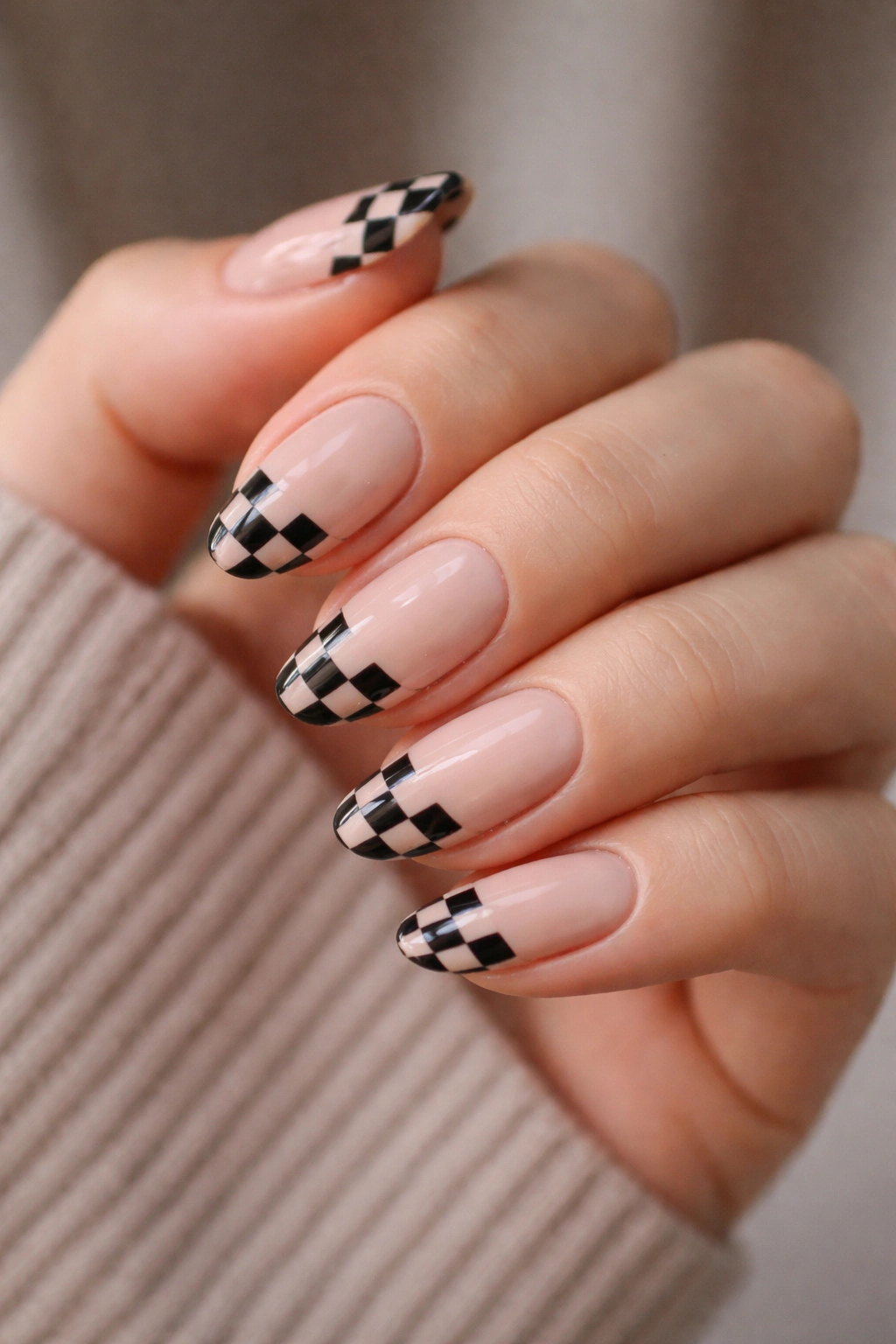 Short almond nails with nude base and black checker tips