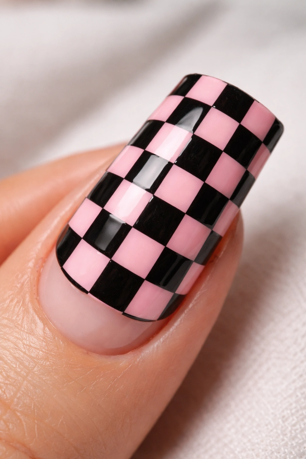 Close-up of a duck nail with black and pink checkerboard pattern.