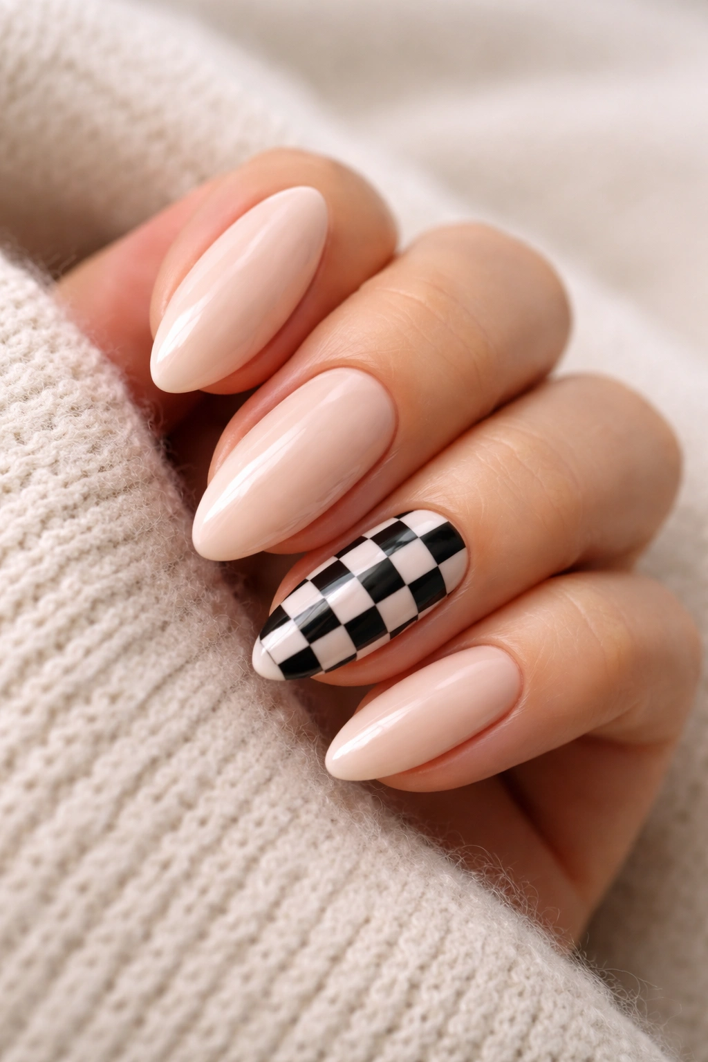 Close-up almond nails with checkerboard accents on nude base