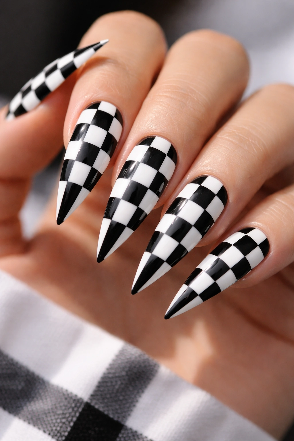 Close-up of stiletto nails with a crisp black and white checkerboard pattern