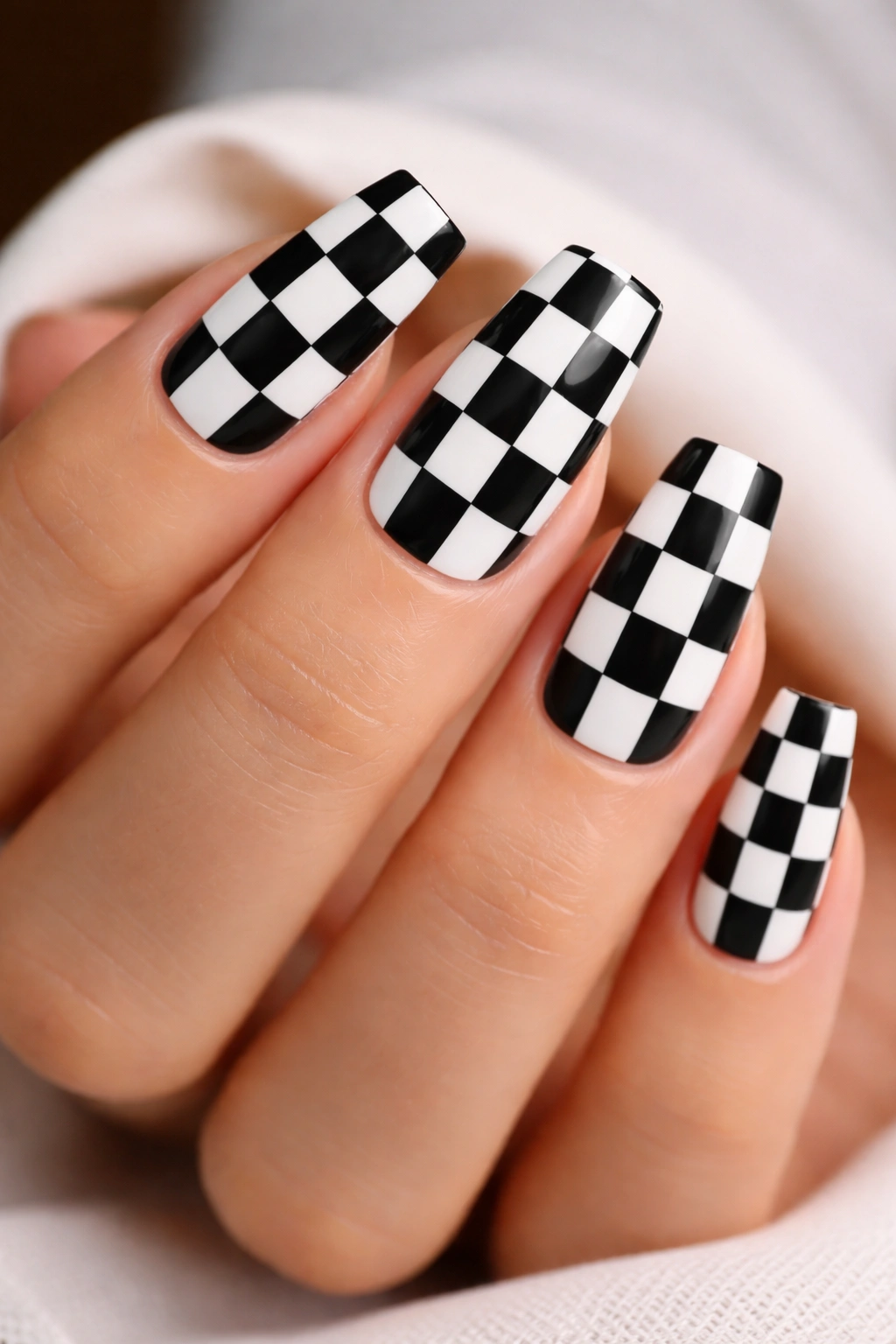 Nails with black and white checkered pattern against a clean backdrop