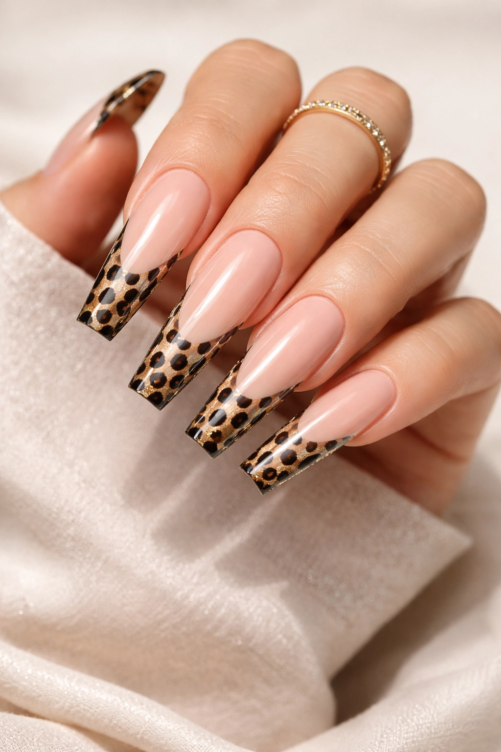 Close-up of extra-long nails with cheetah print French tips on nude base.