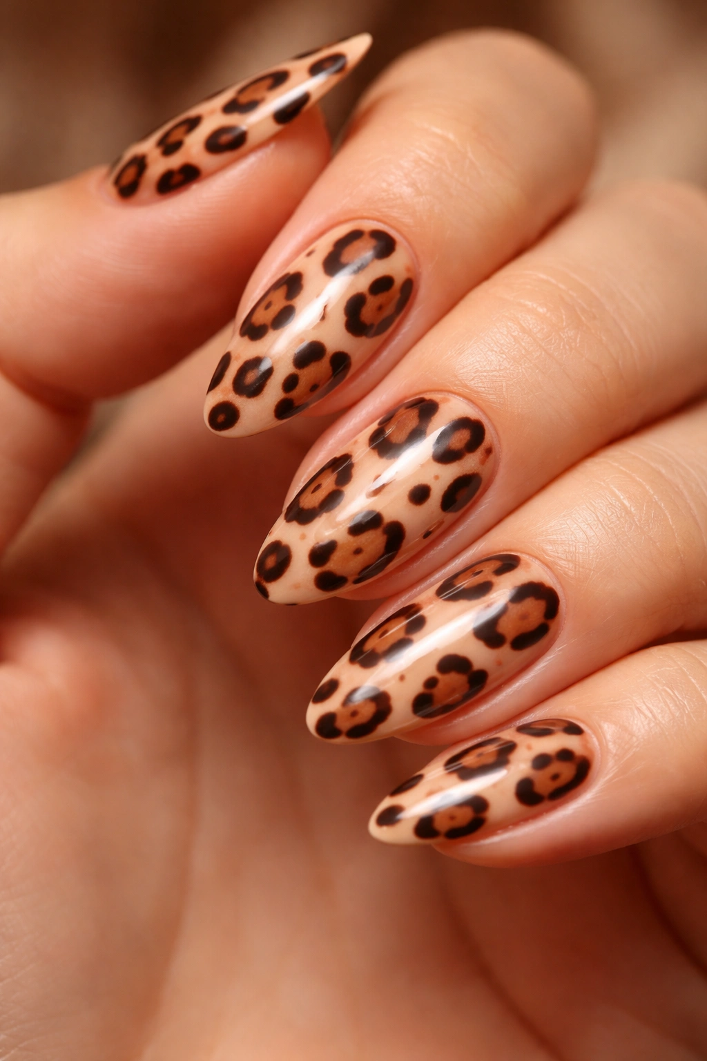 Close-up of cheetah spot nail design with irregular brown spots on peachy nude base.