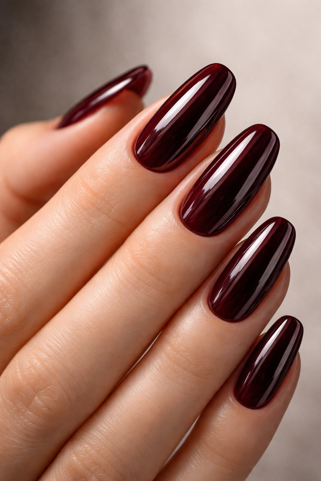 Close-up of nails painted in Cherry Cola deep red with a glossy finish