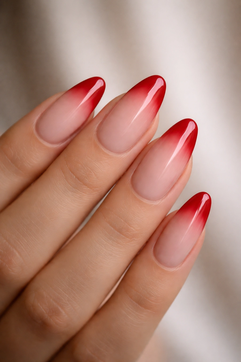 Almond nails with cherry-red tips fading into nude base.
