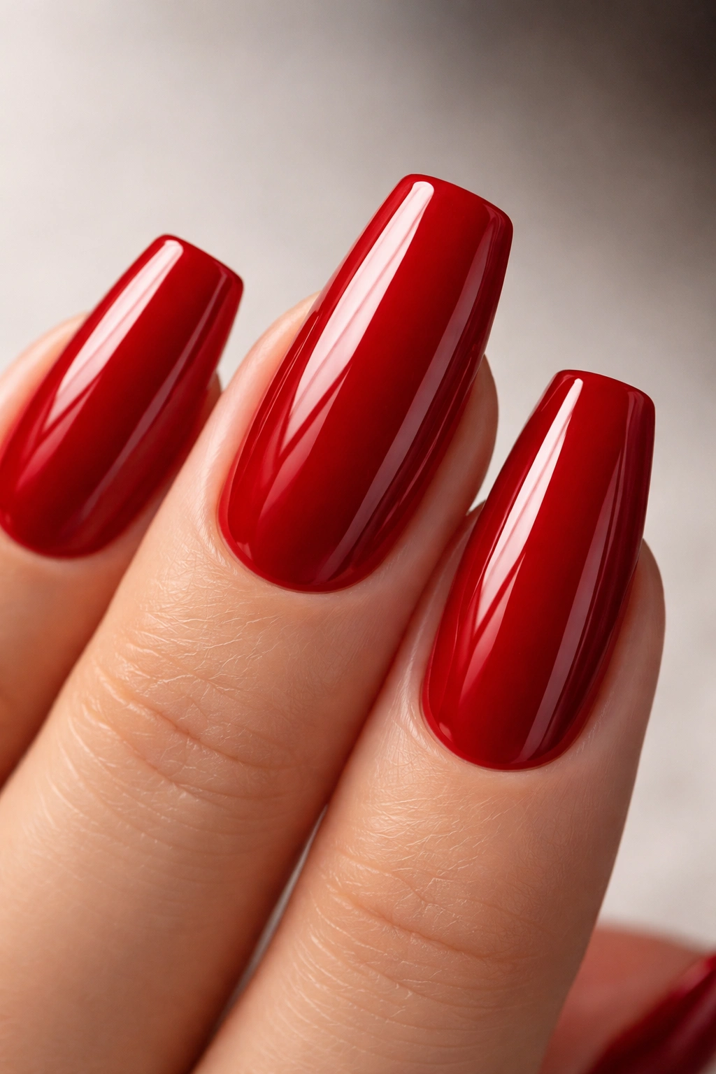 Coffin nail in glossy cherry red with high shine on neutral backdrop