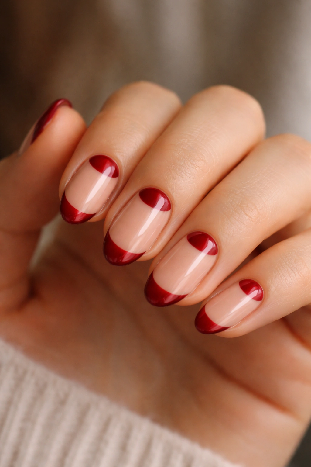 Close-up of short almond nails with cherry red half-moon at the base