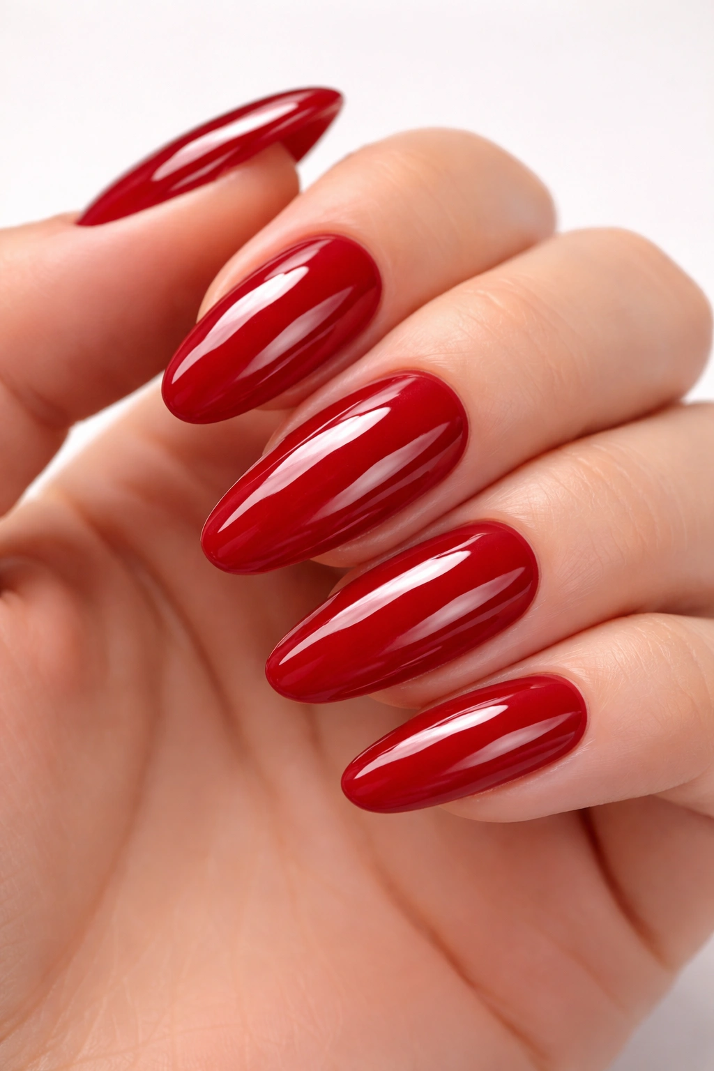 Close-up of glossy cherry red long oval nails