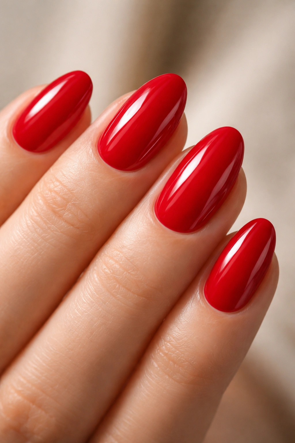 Close-up of cherry red nails on a short almond shape with glossy finish