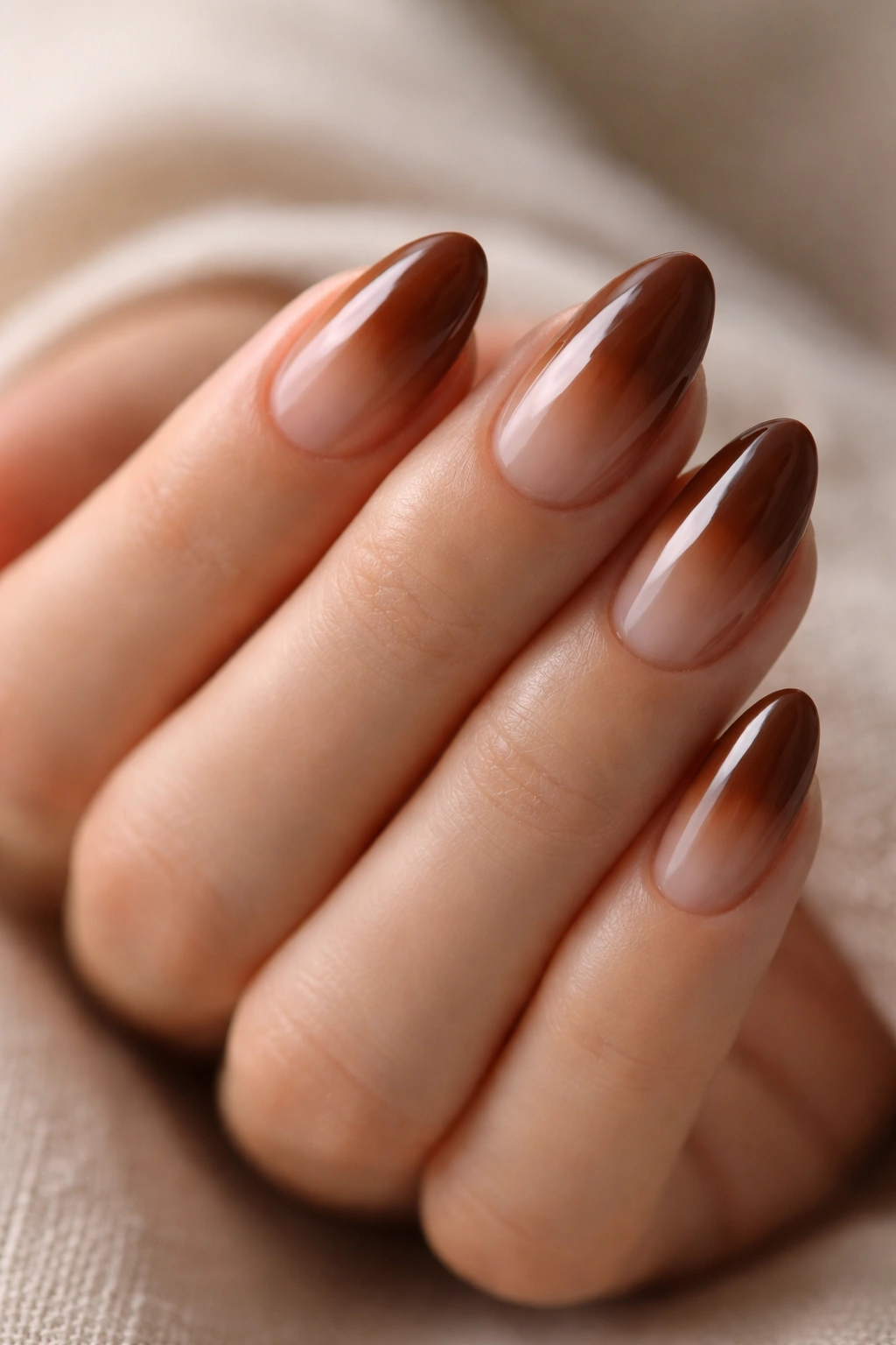 Close-up of short almond nails with chestnut brown sheer base
