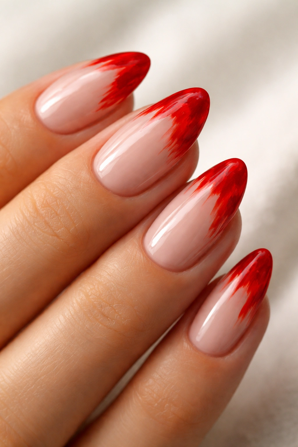Close-up of short almond nails with abstract chili pepper red tips