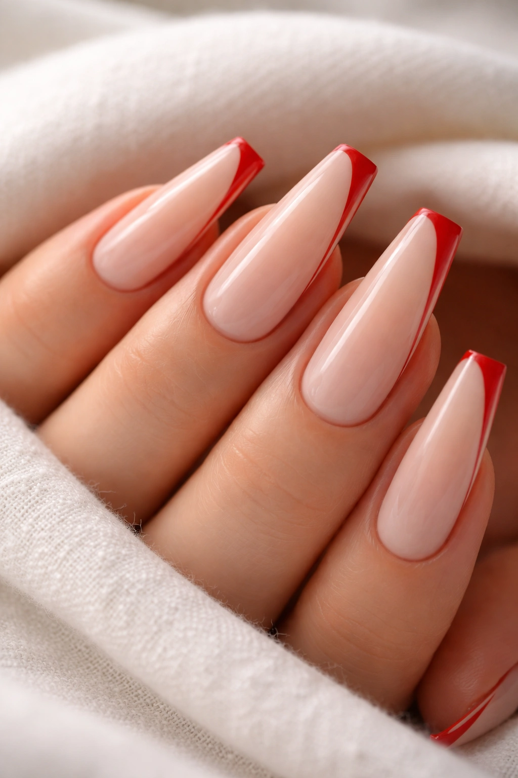 Nails with sheer base and chili red negative-space lines on a ballerina shape.