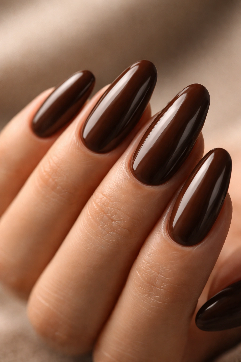 Close-up of chocolate brown long oval nails with glossy finish