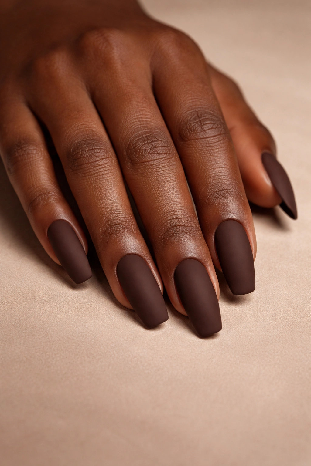 Chocolate brown matte nails on a hand