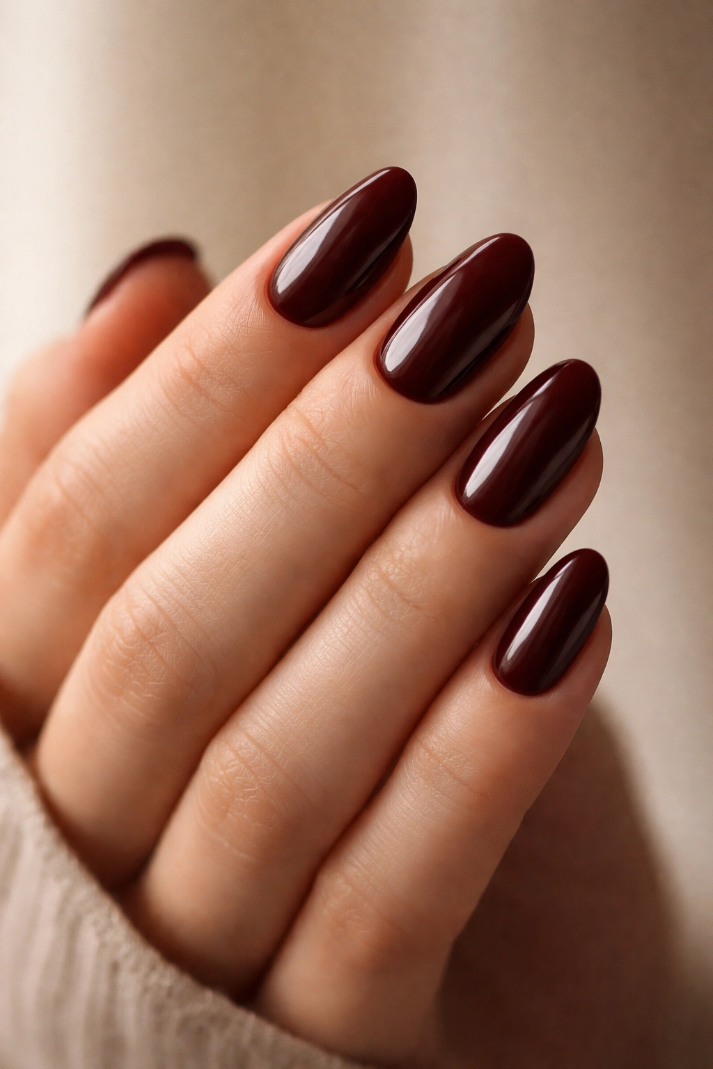 Close-up of short almond nails in chocolate cherry color with glossy finish