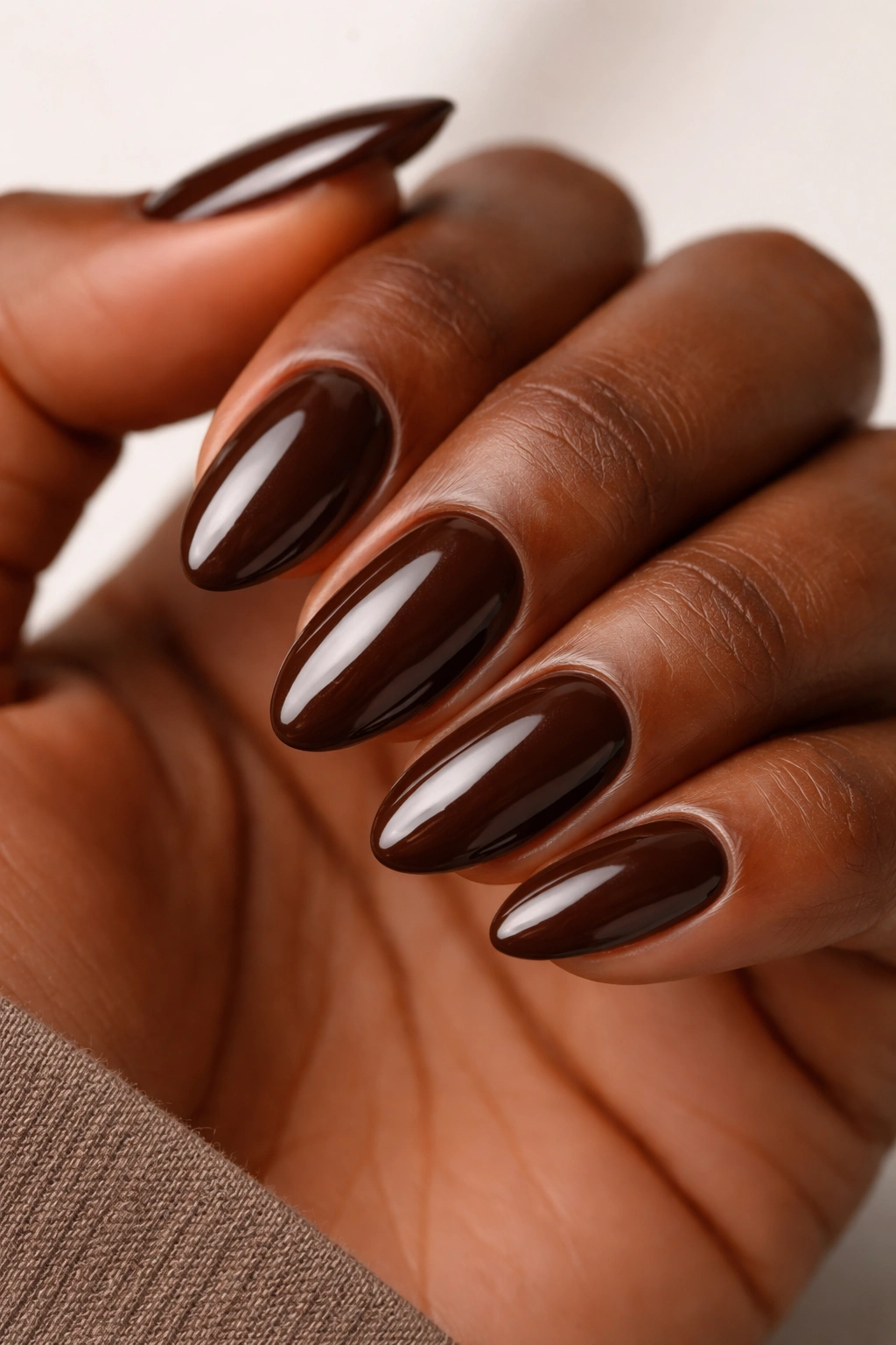 Close-up of chocolate glaze almond nails with glossy finish